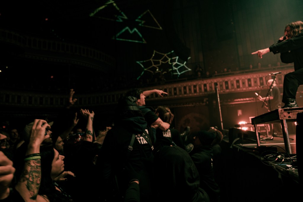Fit For a King performing on stage at The Tabernacle, with a crowd of excited fans in the foreground, raising their arms in celebration.